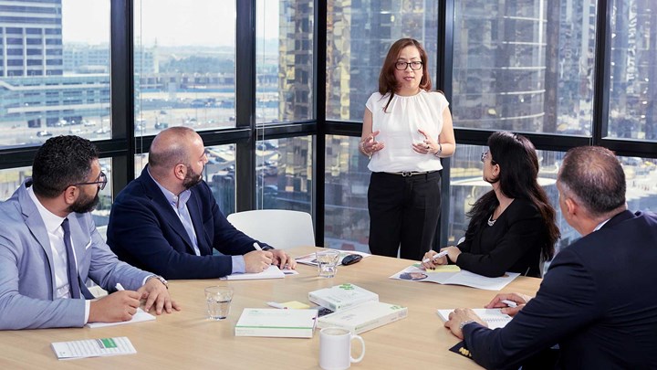 Varios empleados escuchan a una mujer dirigente en una reunión de oficina